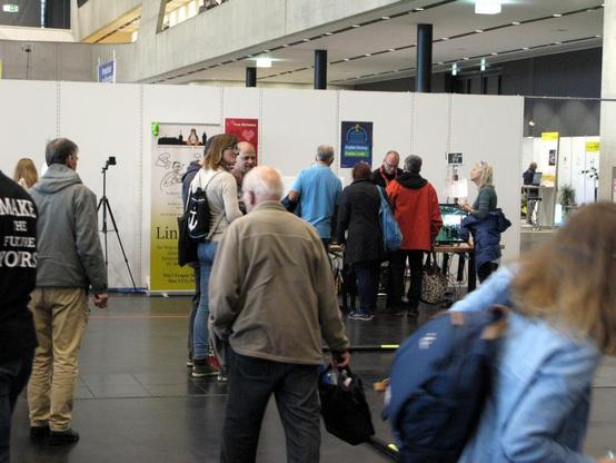 Foto: Die Hack und Make findet 2025 wieder wie 2018/19 in der Messehalle 3C statt. Das Bild zeigt unseren damaligen Stand von 2019. Wir freuen uns wieder, dort in diesem Jahr wieder ausstellen zu dürfen.
Auf dem Bild sind einige Leute zu sehen, welche in Bewegung sind; an unserem Stand lassen sich einige Personen Linux erklären.