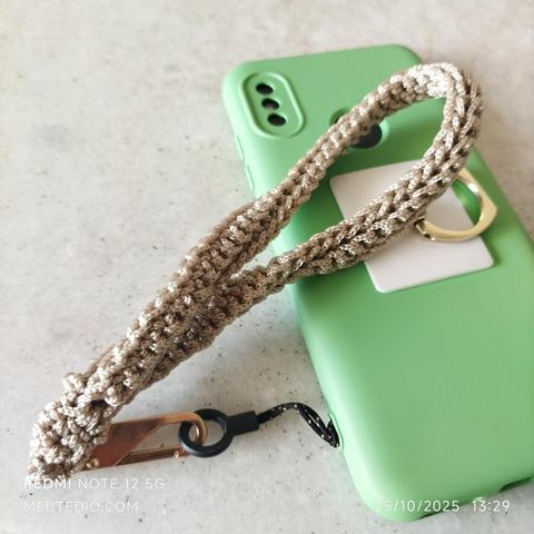 Celular com capinha verde, com uma alça de fio bege brilhante.
