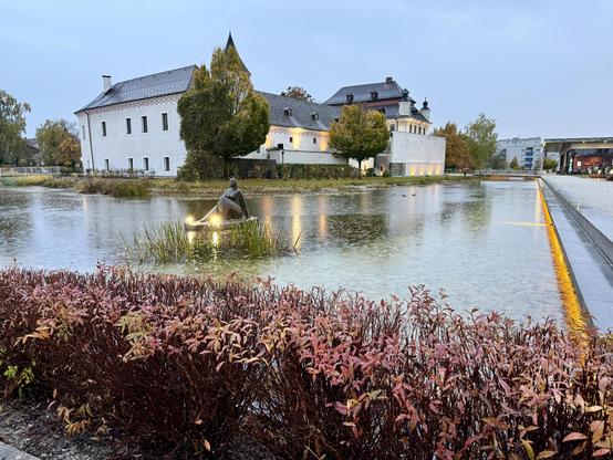 Schloss Traun mit vorgelagertem Wassergraben inklusive Skulptur.