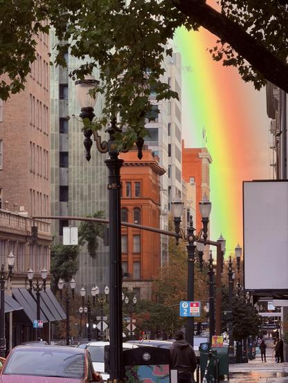 photograph of Washington Street in downtown Portland taken with a Zoom lens and in a break between buildings is an enormous, full spectrum rainbow reaching all the way to the street