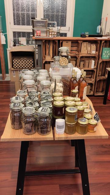 Gläser z.B. mit Schokolade und Honig auf einem Tisch mitten im Laden. Holzoptik.