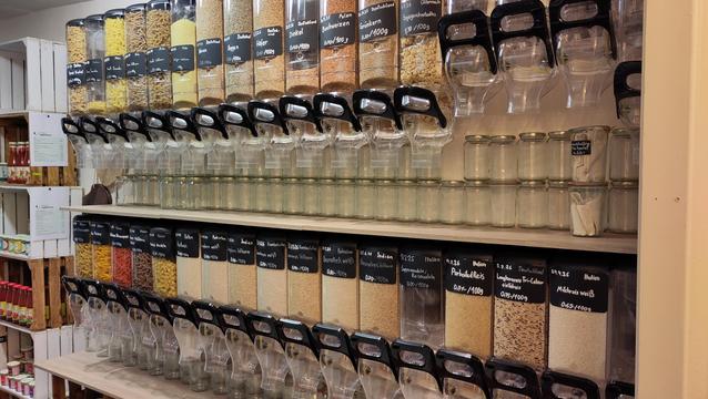 An der Wand hängende Vorratsbehälter in zwei Reihen übereinander mit Nudel, Getreide und ähnlichem