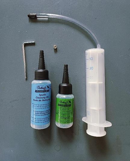 Ein Inbusschlüssel, ein Schräubchen, eine grosse Spritze mit Schlauch, ein Fläschchen mit Spülöl, ein Fläschchen mit Ganzjahresöl