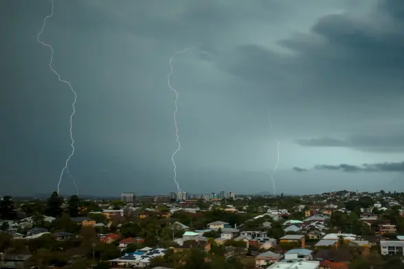 A drone photo of a suburban brisbane skyline, with 3 strikes of lightning striking across the horizon at once