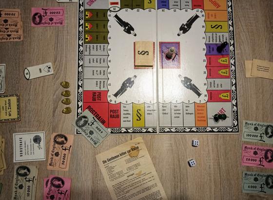 Das Spielfeld von oben. Es erinnert an Monopoly. Geld liegt auch rum, Spielgeld natürlich.