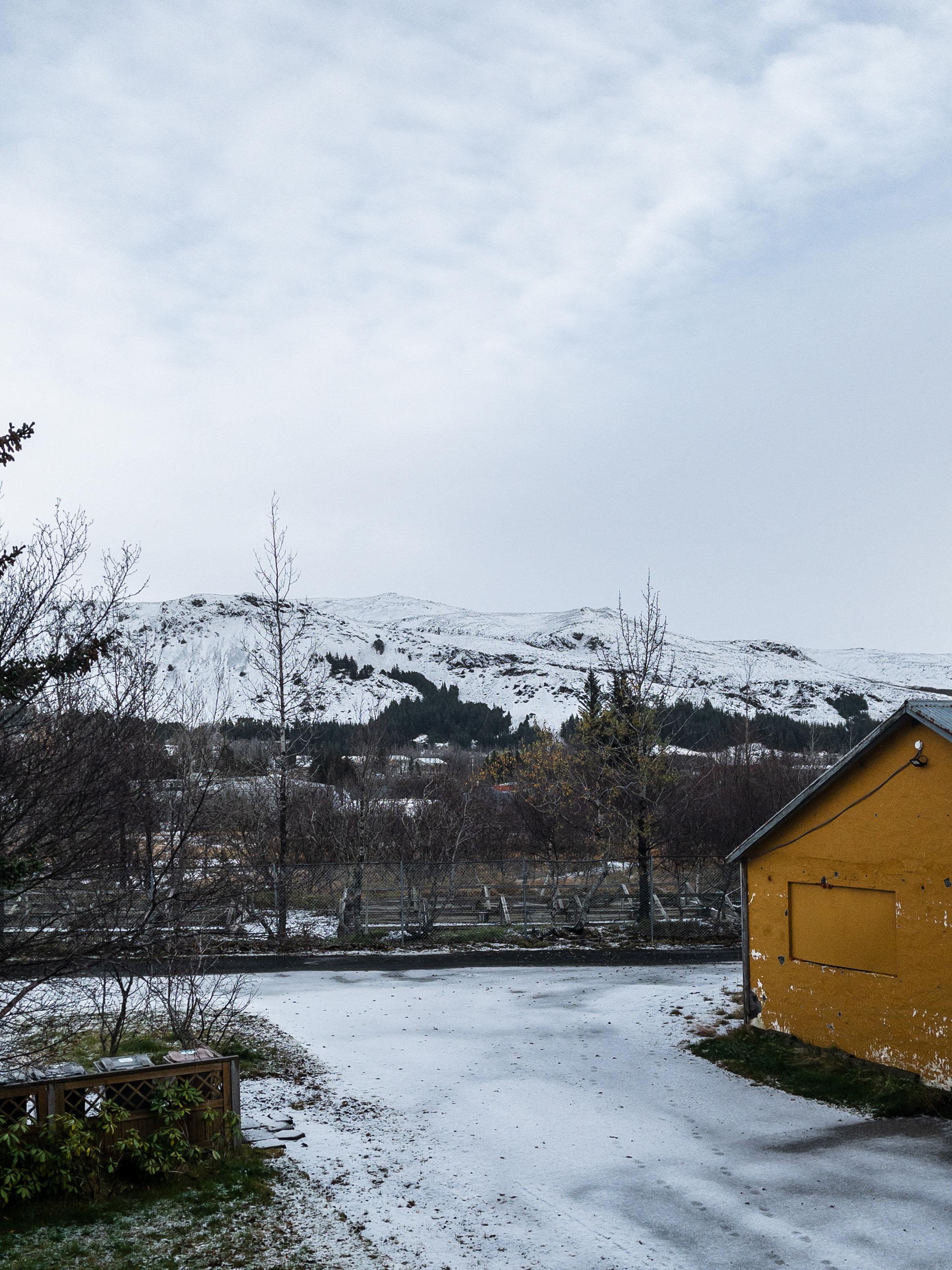 A view of a driveway and mountains, both covered in snow.