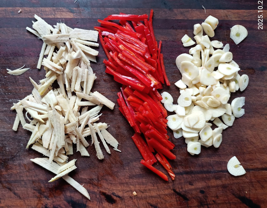 viel geschnittener Ingwer, Knoblauch + rote Chili auf einem Brett