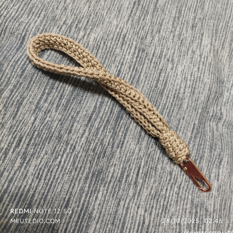 Alça de crochê bege com mosquetão pequeno dourado.