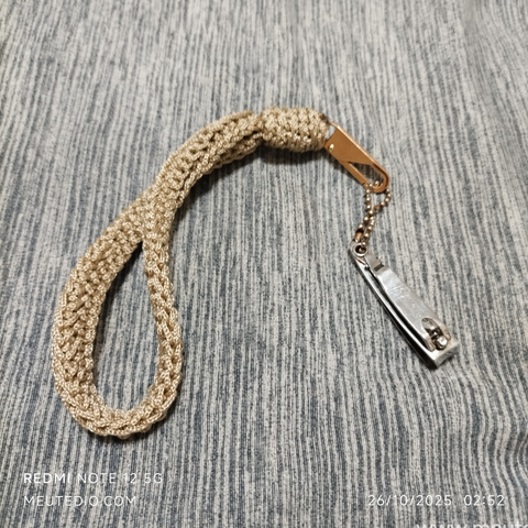 Alça de crochê bege acoplada a um cortador de unha.