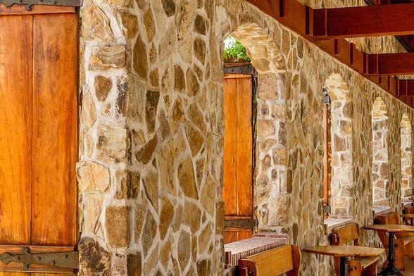 Jacuzzi Winery

You’re standing in front of a rustic winery bathed in warm, late-afternoon light. The building is made of aged stone and weathered wood, giving it a timeless, handcrafted feel—like something built with care and meant to last. The textures are rich: rough stone that might feel cool and gritty to the touch, and wooden beams that have soaked up decades of sun and rain.
The architecture is classic and inviting, with arched doorways and terracotta roof tiles that hint at Mediterranean influence. There’s a sense of quiet elegance, not flashy or modern, but grounded and earthy. Imagine the scent of crushed grapes lingering in the air, mingling with the faint aroma of oak barrels and sun-warmed soil.
In the foreground, there may be a path or courtyard—perhaps cobblestone or gravel—leading you toward the entrance. It feels like a place where stories are told over wine, where laughter echoes off the walls, and where the land itself is part of the experience.
The light in the image is golden, casting soft shadows and highlighting the textures of the stone and wood. It’s the kind of light that makes everything feel a little more magical, a little more alive.