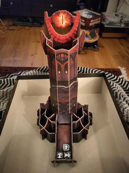Ein aus Pappelementen zusammengesteckter Würfelturm in Firm von Barad-Dûr, Saurons Turm aus Der Herr der Ringe, inklusive Saurons Auge. Unten im Turm sind drei schwarz-weiße Würfel mit abgestorbenen Bäumen drauf.