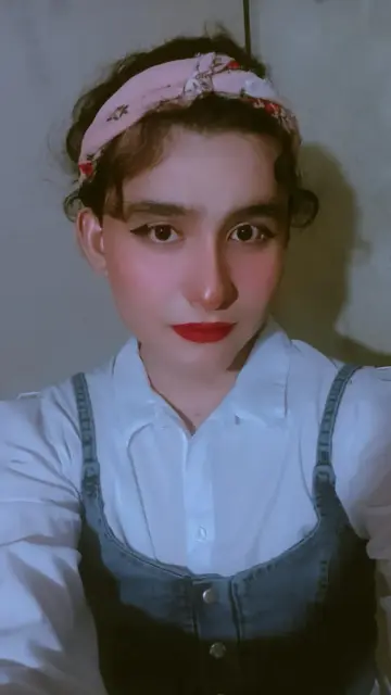 A selfie wearing a denim top with a white shirt and a pink headscarf.