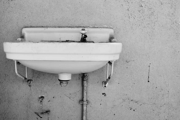 B&W-Aufnahme eines Waschbeckens, welches nicht mehr genutzt wird bzw. außer Betrieb ist.