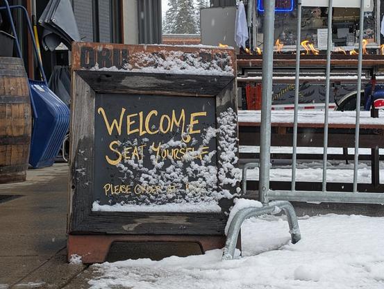 The Dru Bru brewery sign welcomes people to seat themselves as snow falls around it