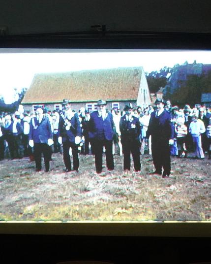 Foto aus einem alten Super8 Film mit Fünf Männer in Schützentracht vor einer Gruppe von Menschen und unserem Schweinestall im Hintergrund