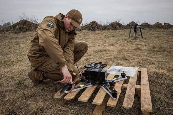 Dmytro Romanchenko, 22, director of Raptor Engineering, adjusts parts of an FPS front before flying a fiber-optic-controlled FPV drone from a launch pad at a test site in Ukraine, spring 2025