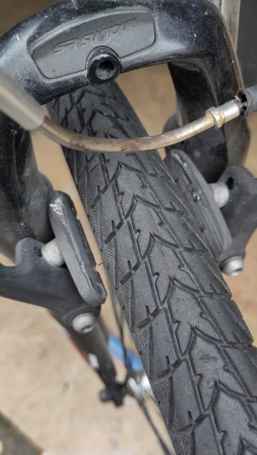 Gros plan sur le frein avant d'un vélo. Il s'agit de freins vbrakes avec l'étrier pour qu'on voit l'état des patins. Les patins sont usés jusqu'au support métallique