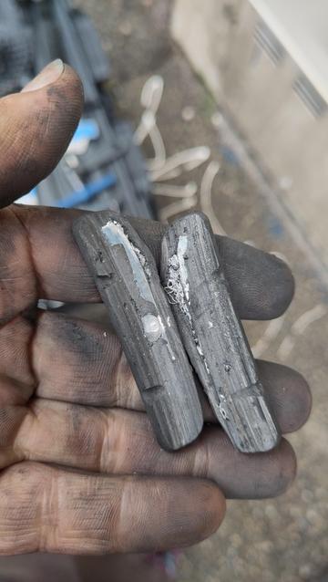 Les deux patins démontés tenus en main. On voit de grosses zones métalliques