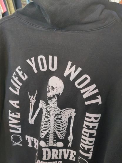 the back of a black sweatshirt with a skeleton surrounded by the words 'live a life you wont regret' around it