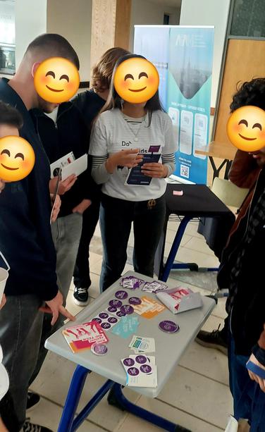 A small table woth stickers related to Rise Against Big Tech campaign and 6 youngsters around the table.