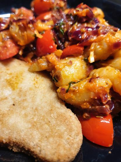 A plate with anamma 'VegoSchnitzel', Potato Gnocchi w/ Pesto alla Calabrese, and Red Onion, Fresh Tomato & Basil sauce.