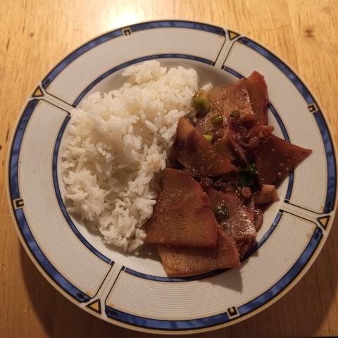 Teller auf Holztisch mit Reis, roten Radi geschmort mit Frühlingszwiebeln, Zwiebeln und Ingwer