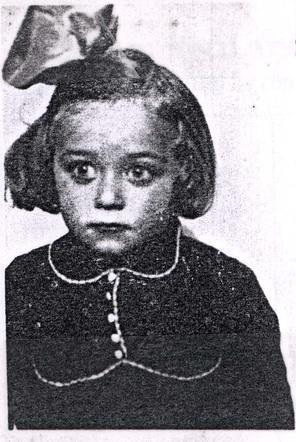 Black and white photograph of a young girl with a large bow in their hair, wearing a collared dress with button details.