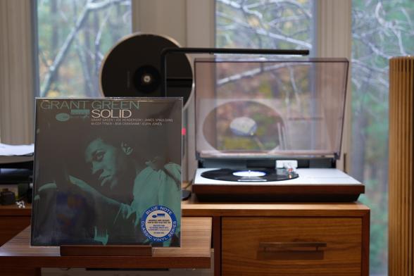 Grant Green - SolidLP cover.

A green-tinted black and white photo of Grant Green playing his guitar.

The black LP plays on a vintage, restored Bang & Olufsen Beogram 4000 linear-tracking turntable to the right.