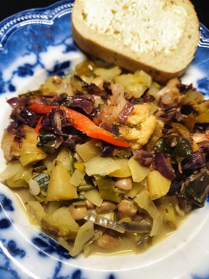 A bowl of Cabbage, Leek & Pinto Bean soup, topped w/ coriander fried vegetables. Served w/ poppy seed bread.