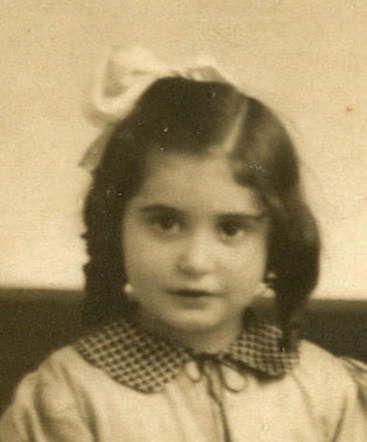 An old sepia-toned portrait of a young gilr with a bow in their hair, wearing a checkered outfit.