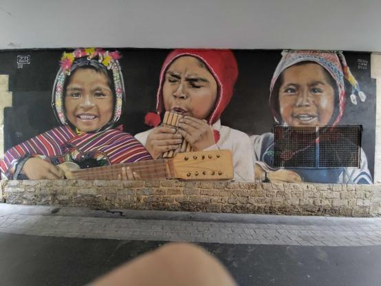 trois portraits en bustes d'enfants jouant de la musique, portant des bonnets typiques des Andes ; une petite fille à guitare, un garçon à flûte de pan et un autre à la guitare