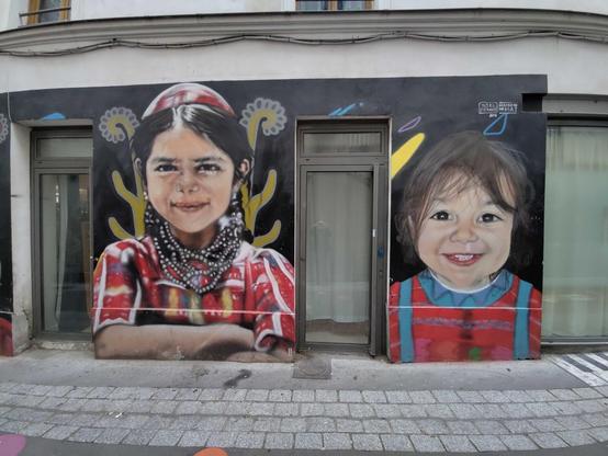 portrait de deux enfants : une fille souriante aux habits rougeoyants et un petit enfant rigolard