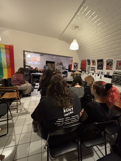 Zdjęcie z Banhofu przedstawiające osoby siedzące na krzesłach przed wykładowczyniami.