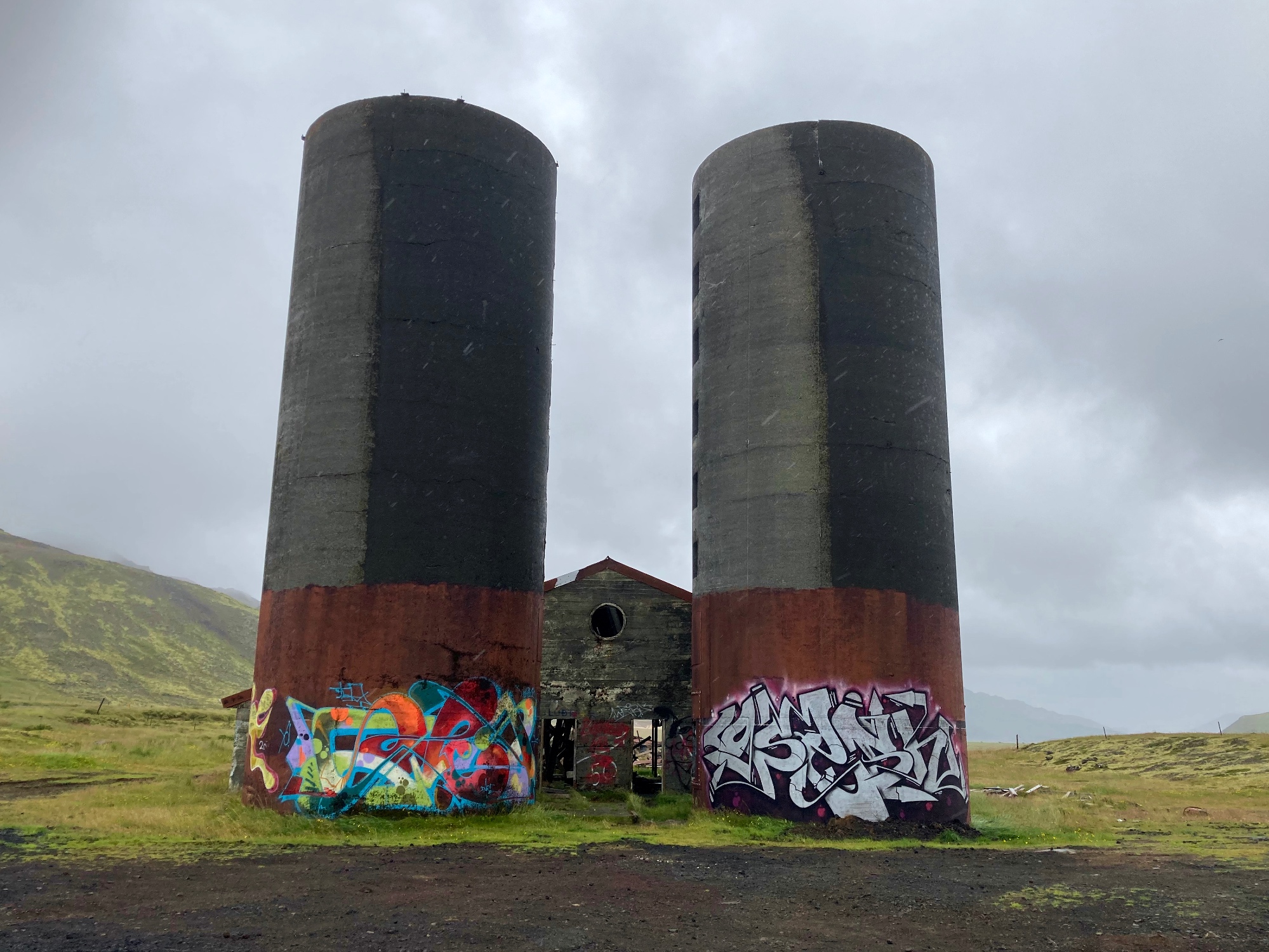 Abandoned silos and a barn, covered in graffiti.