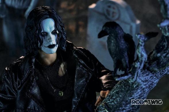 Eric Draven stands in a Graveyard looking up at a crow that's sitting in a tree