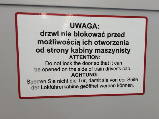 Komunikat w trzech językach. Po polsku:

"""
UWAGA: drzwi nie blokować przed możliwością ich otworzenia od strony kabiny maszynisty.
"""

Po angielsku:

"""
ATTENTION: Do not lock the door so that it can be opened on the aide of train driver's cab.
"""

Po niemiecku:

"""
ACHTUNG: Sperren Sie nicht die Tür, damit sie von der Seite der Lokführerkabine geöffnet werden können.
"""