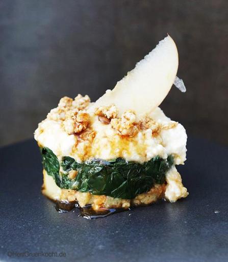 Ein kleines Törtchen aus in Knoblauch gedünstetem Spinat auf Dinkel-Hafer-Crunchy mit einer Apfel-Joghurtsauce und Ahornsirup