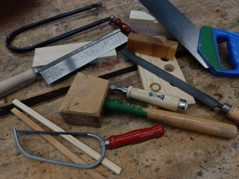 Diverse Werkzeuge zur Holzbearbeitung liegen auf einer hölzernen Arbeitsplatte.