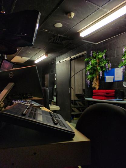 A look at the booth. The back wall is black and there's some plastic plants. The doorway with the spiral staircase goes up to the rafters.
