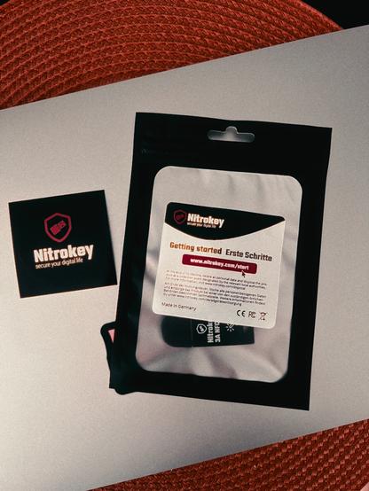 A Nitrokey 3 package with a nitrokey sticker on top of a MacBook Air