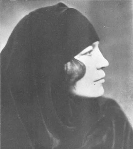 I women photographed in black and white in profile. She wears a headdress of black.