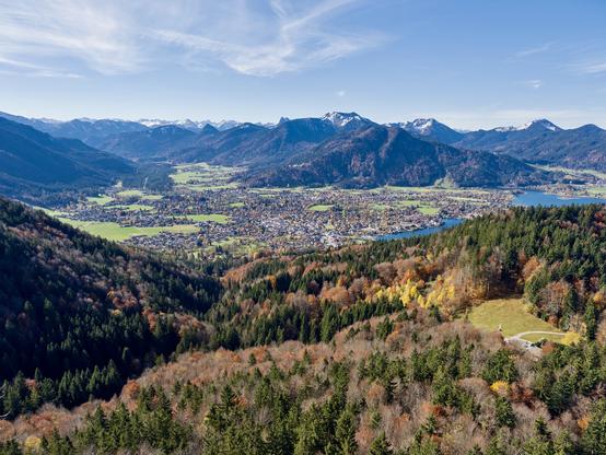 Autumn colours lead eye into green fields of valley enclosed by mountains