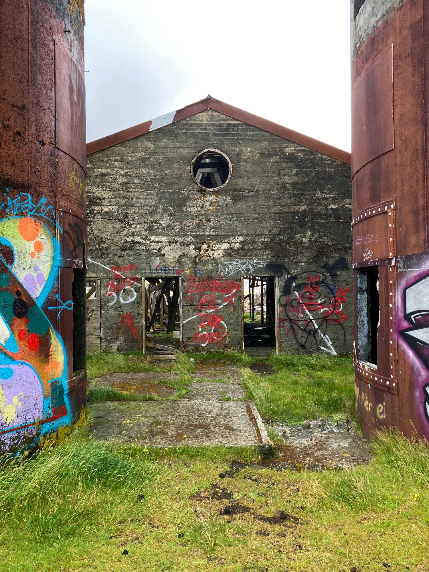 An abandoned barn with a round window covered in graffiti.