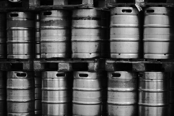 The image shows multiple large, cylindrical metal kegs arranged closely together in rows. Each keg has a smooth, reflective surface with visible horizontal seams. The black-and-white color scheme emphasizes the textures and light reflections on the metallic surfaces.

 Das Bild zeigt mehrere große, zylindrische Metallfässer, die dicht beieinander in Reihen angeordnet sind. Jedes Fass hat eine glatte, reflektierende Oberfläche mit sichtbaren horizontalen Nähten. Der schwarz-weiße Farbton hebt die Texturen und Lichtreflexionen auf den metallischen Oberflächen hervor.