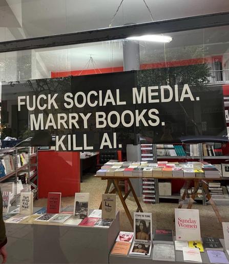Imagen vitrina librería con frase en vidrio “fuck social media , marry books kill AI”