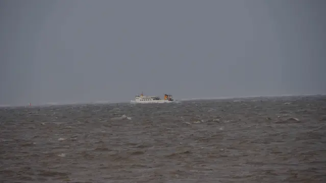 Weißes kleines Schiff auf grauem aufgewühlten Meer