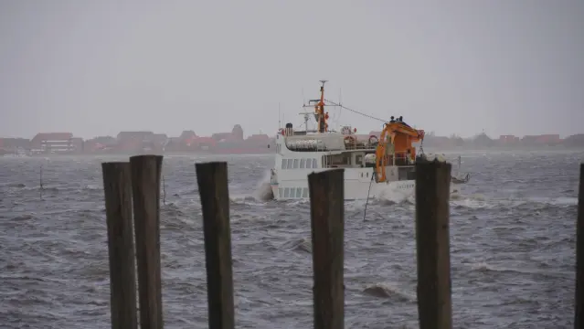 Weißes Schiff bei der Hafenausfahrt. Graubraunes Wasser Spritzt