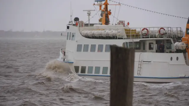Weißes Schiff bei der Hafenausfahrt. Graubraunes Wasser Spritzt
