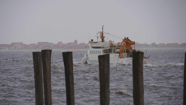 Weißes Schiff bei der Hafenausfahrt. Graubraunes Wasser Spritzt