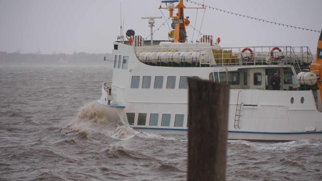 Weißes Schiff bei der Hafenausfahrt. Graubraunes Wasser Spritzt